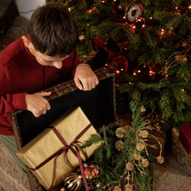 Un enfant qui ouvre un coffre avec des cadeaux et des boules de Noël