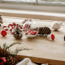 Des pommes de pin autour d'une boule de Noël blanche avec des champignons en verre à l'intérieur