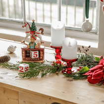 Une décoration de Noël avec des bougies blanches et rouges, des branches de sapin et une éphéméride
