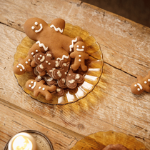Des biscuits sucrés en forme de bonhommes en pin d'épices dans une assiette ocre sur une table bois