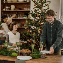 Un papa et son fils qui mettent la table en posant des assiettes blanches sur la table