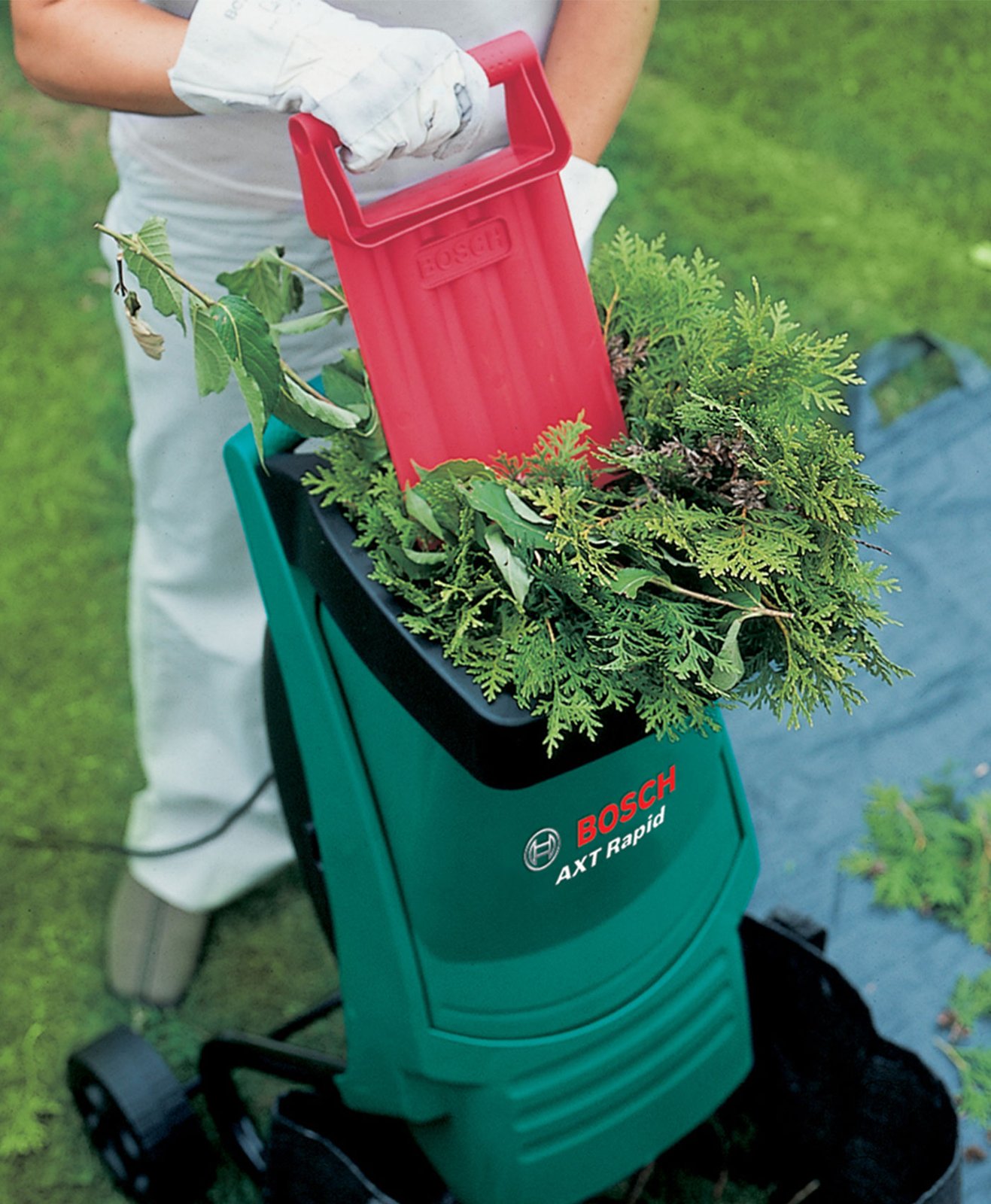 Un homme broie ses déchets organiques du jardin avec un boyeur