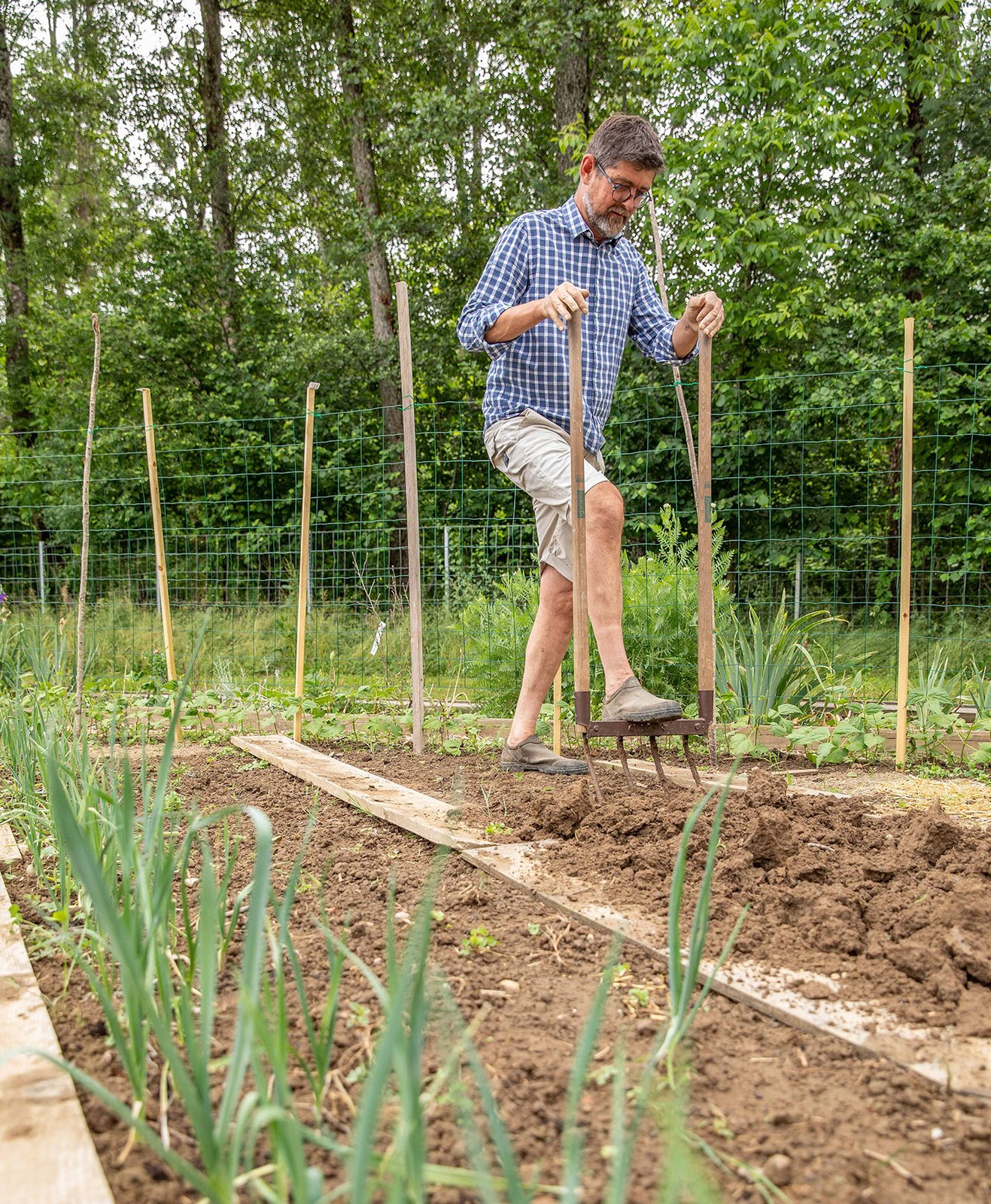 Un homme travaille le sol de son potager en pleine terre