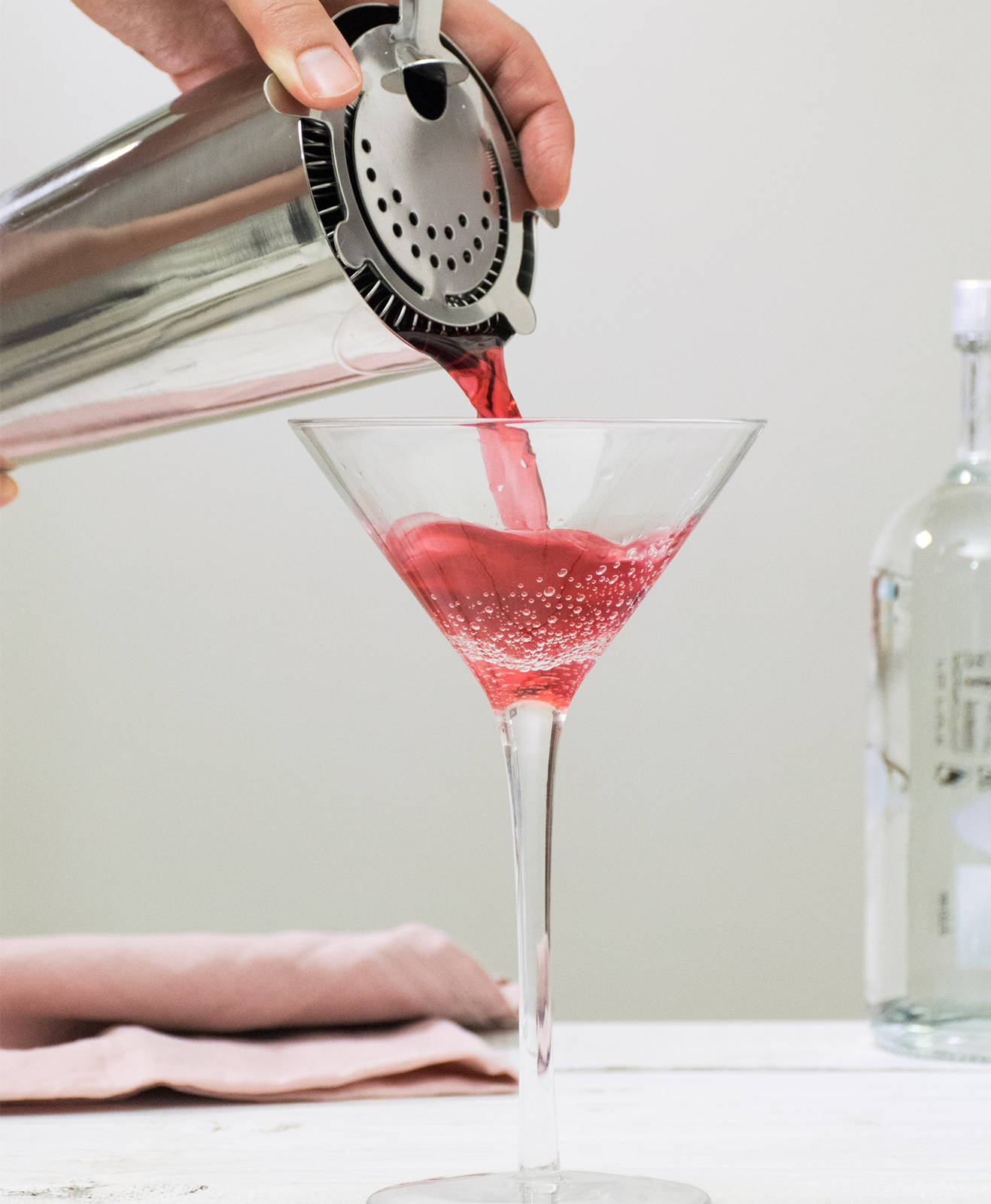 Une personne prépare un cocktail à base de vodka dans un shaker