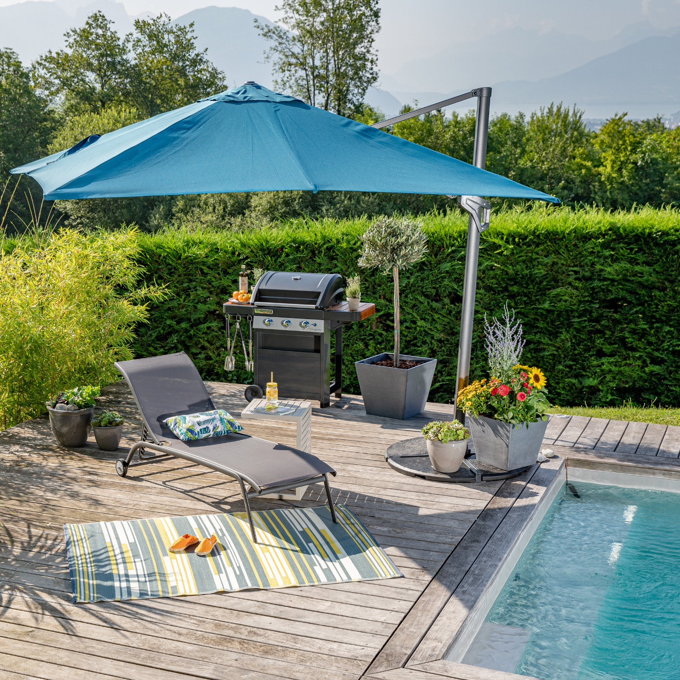 Parasol bleu à côté d'une piscine et qui protège un transat du soleil