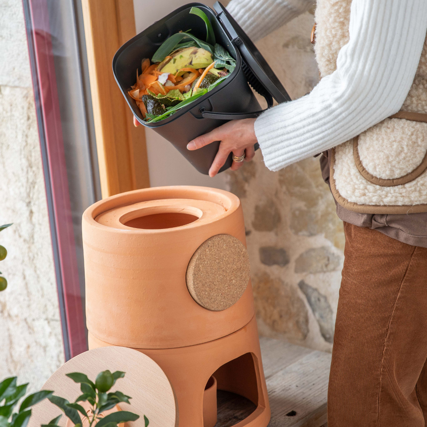 Femme qui verse du composte dans son composteur d'intérieur