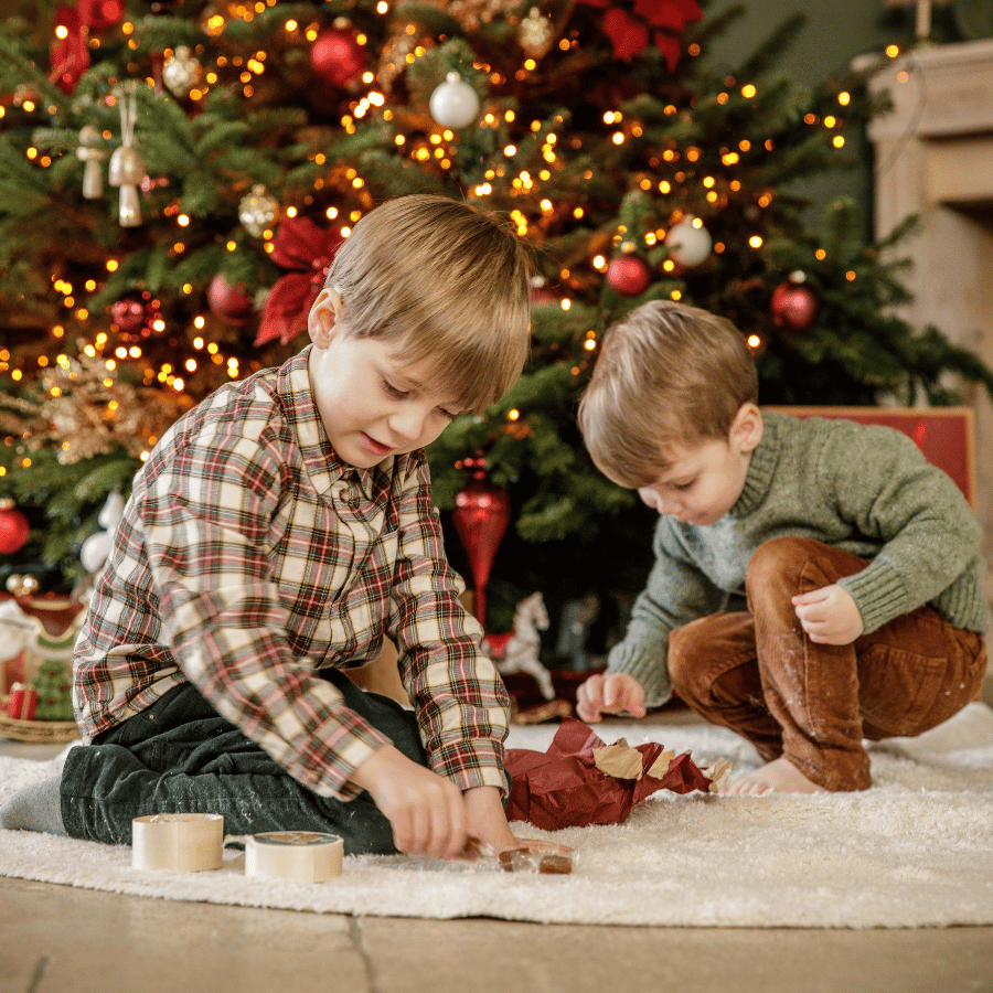 Petit garçon lit un livre devant la sapin de Noël