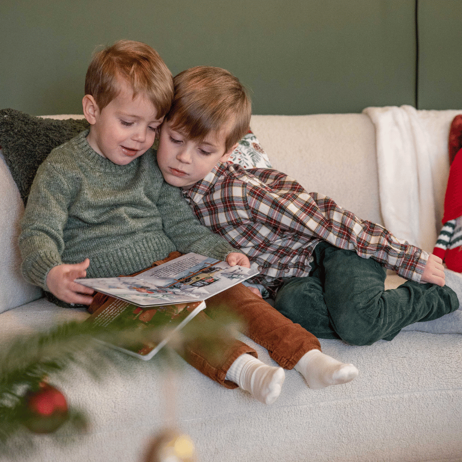 Enfant lisant un livre au pied du sapin de Noêl