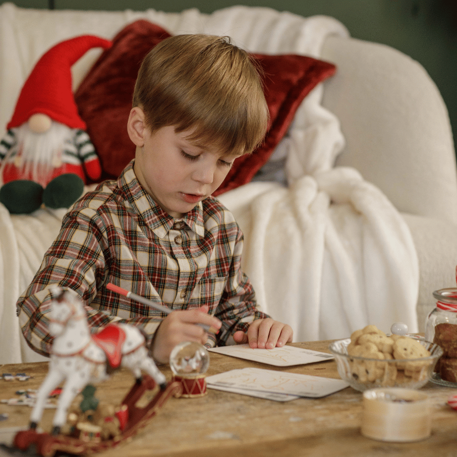 Enfant écrivant sa lettre au Père-Noël sur son bureau