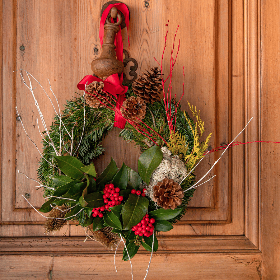 Couronne de Noël verte et blanche accrochée sur une porte d'entrée