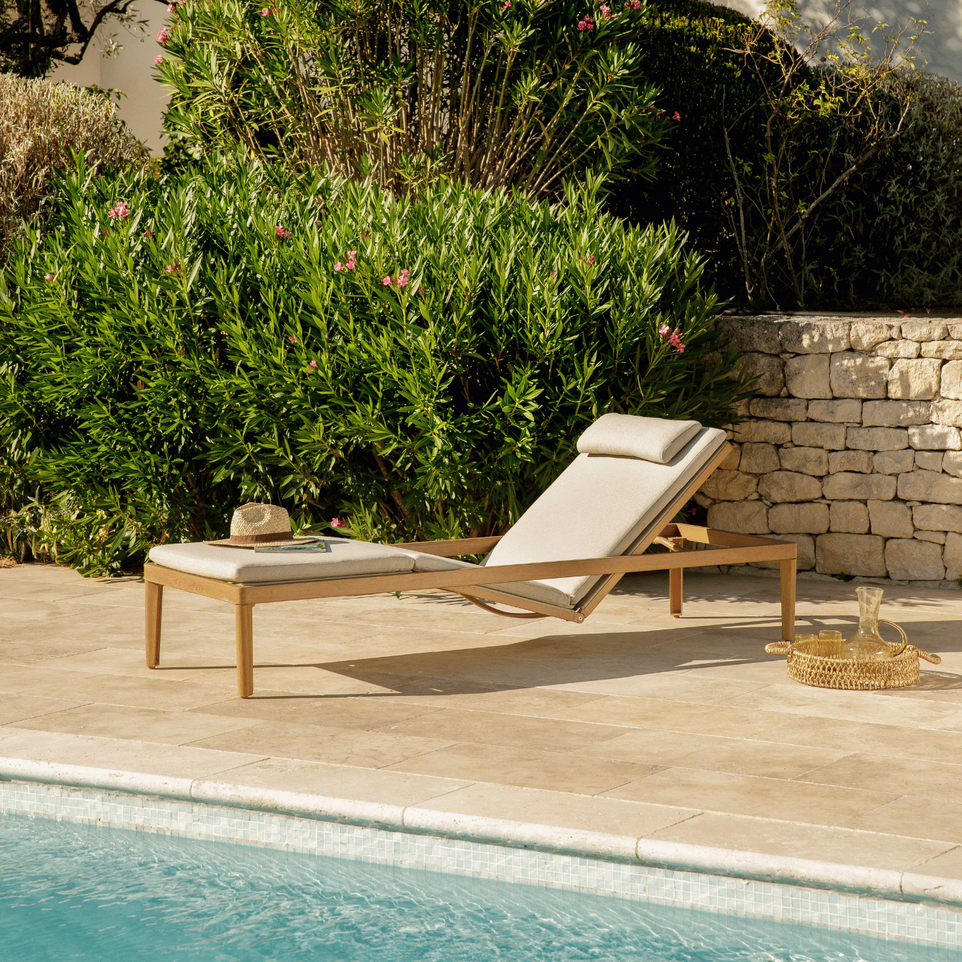 Un transat au bord de la piscine avec un chapeau posé dessus