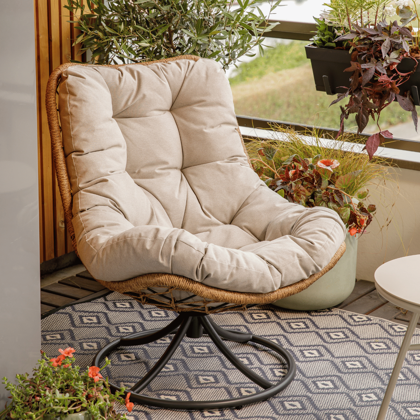 Un fauteuil pivotant blanc sur une terrasse, entourée de plantes.