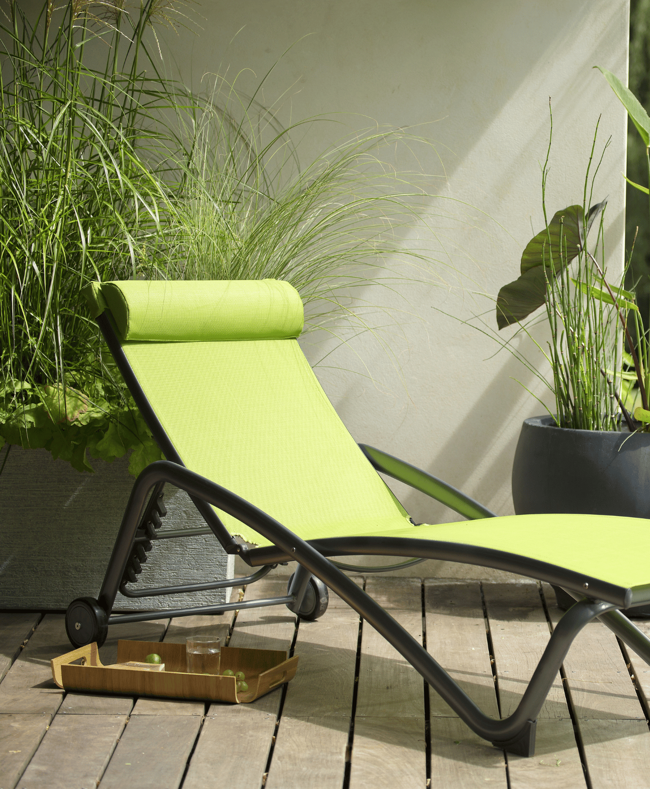 Un bain de soleil vert en aluminium sur une terrasse en bois