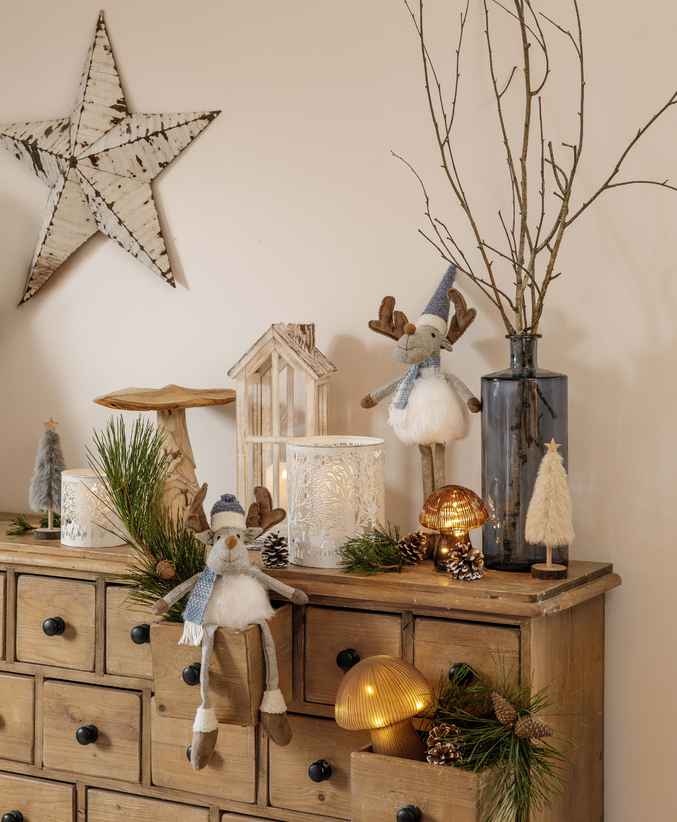 Un meuble décoré pour noël avec de la petite décoration, des branches et des bougies