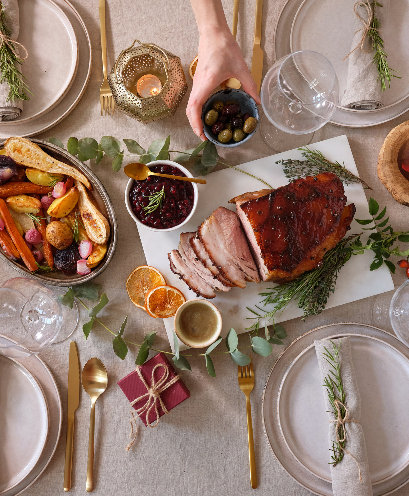 Table de noël remplie de nourriture : un rôti, des légumes et des olives