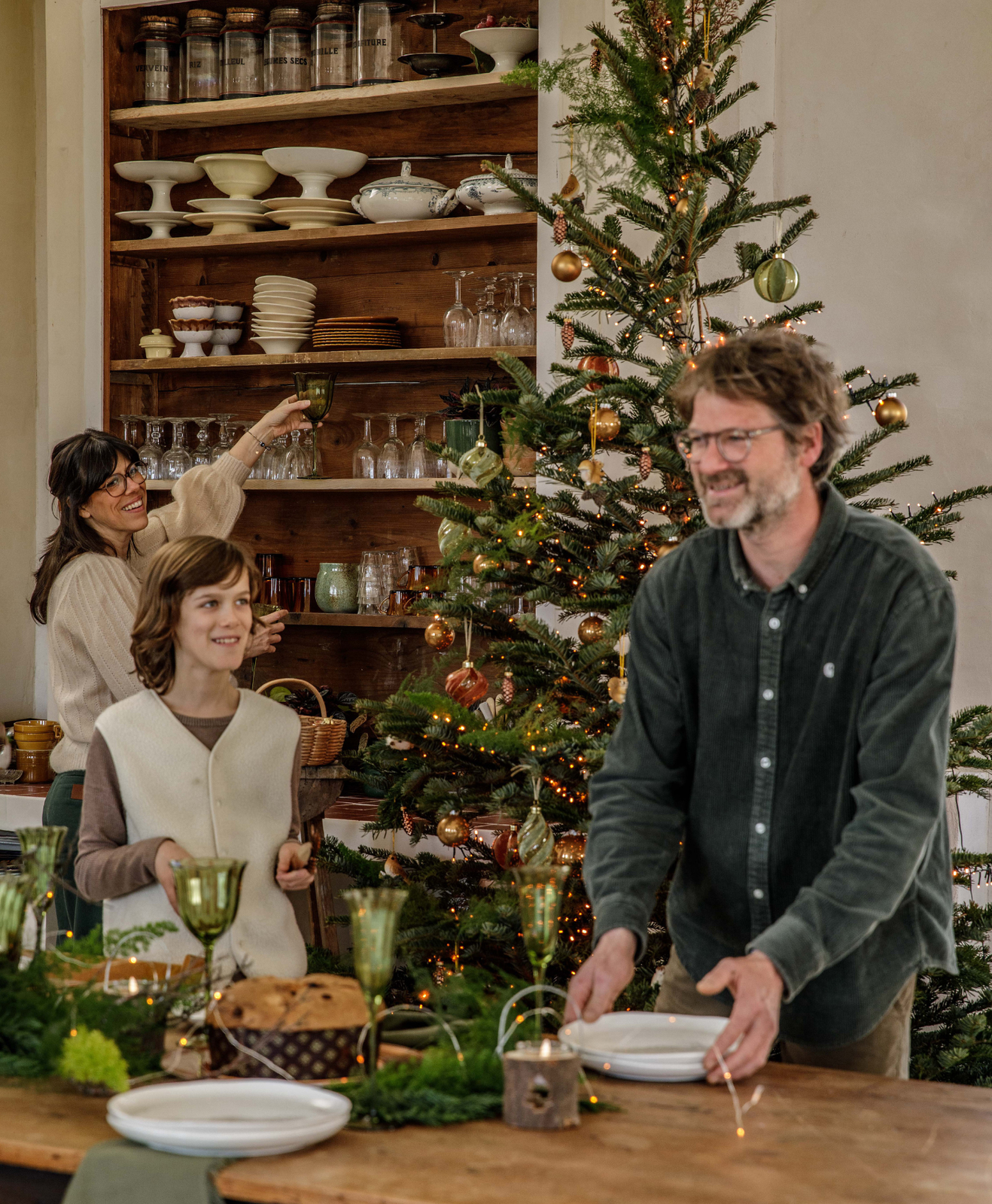 Une famille avec un enfant qui dresse la table de noël