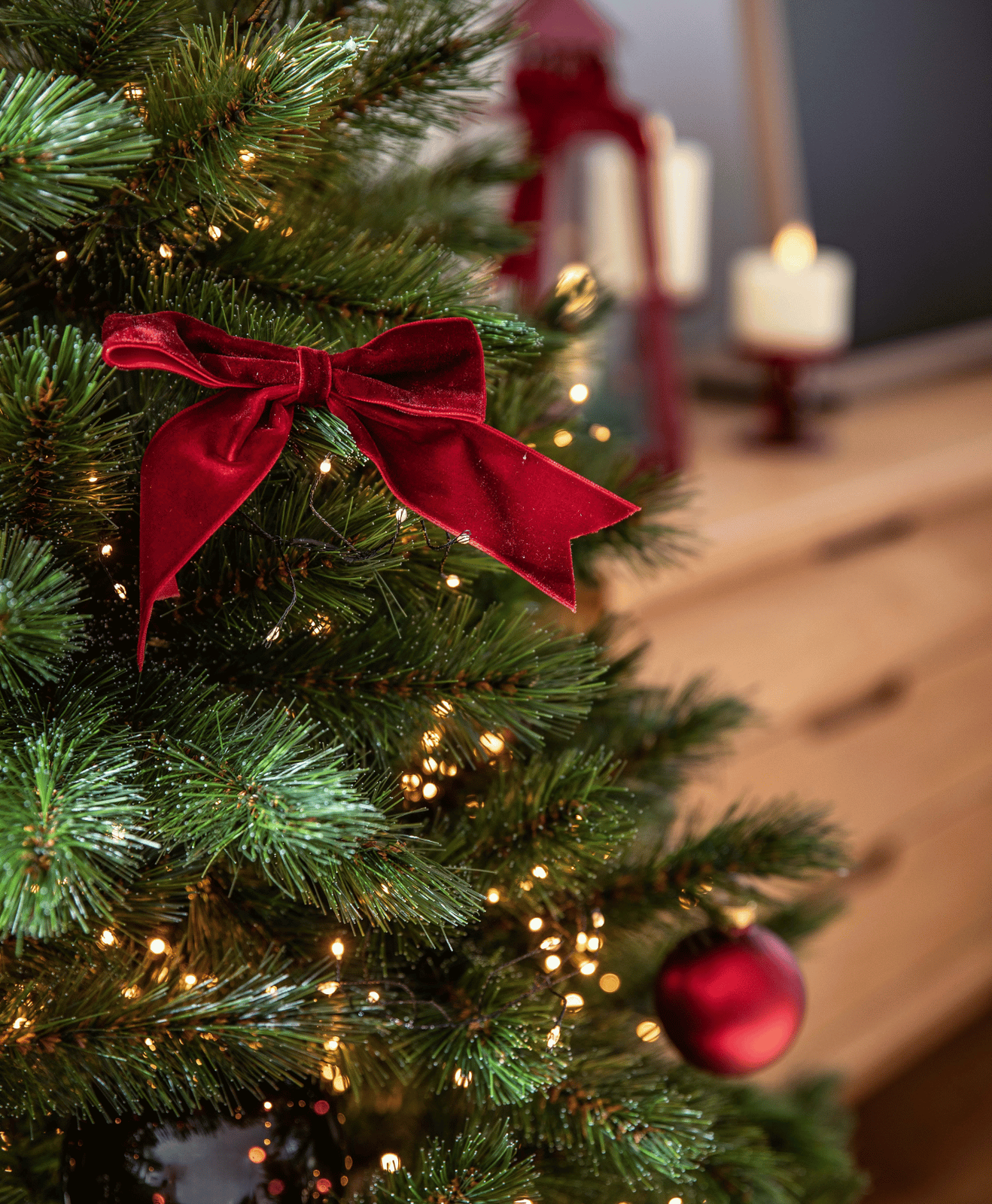 Un zoom sur un sapin artificiel avec un ruban rouge et des lumières intégrées