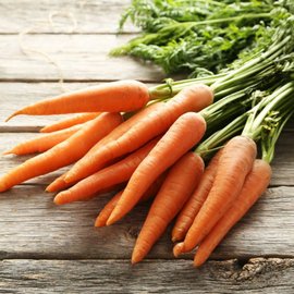 Des carottes qui sont posées sur une table en bois