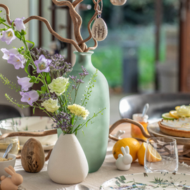 Décoration d'une table de Pâques avec un vase vert, des œufs de pâques, des lapins de pâques