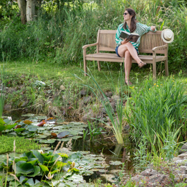 Une femme au bord d'une mare dans son jardin