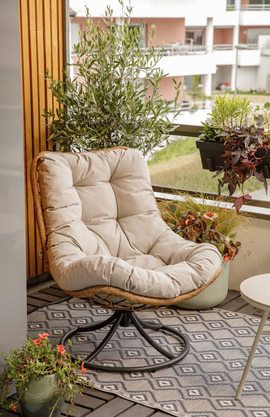 Un fauteuil confortable sur un balcon urbain avec des pots de fleurs et un tapis