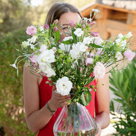 Une femme qui tient dans ses mains un bouquet de fleurs des champs dans un vase pour la fête des mères