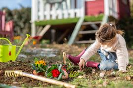 Une petite fille qui joue avec un râteau et un arrosoir dans un jardin