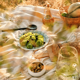 Une salade de tomates vertes avec des olives noires, sur une nappe pour un pique-nique en pleine nature