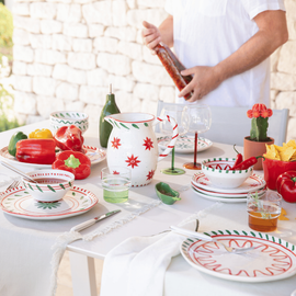 Un homme qui se tient près de sa table aux couleurs de blanc, rouge et vert et avec de la vaisselle graphique