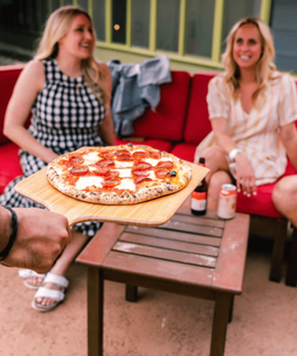 Personnes autour d'une table avec des boissons et une pizza.