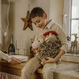 Un enfant qui tient la peluche d'un petit renne nommé Fergus dans les bras