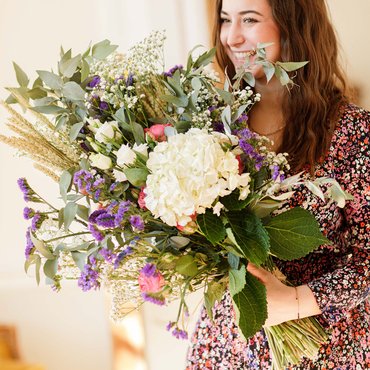 Une femme sourit en portant un bouquet de fleurs