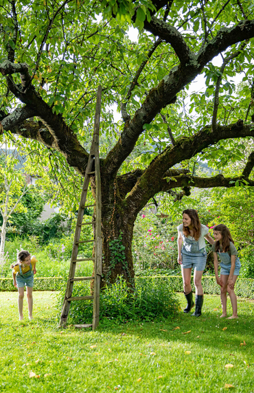 Une femme en train de jouer avec ses enfants dans un jardin