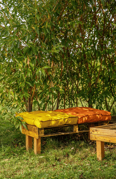 Un salon de jardin avec des coussins à l'ombre de bambou