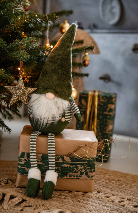 Un gnome assis sur un cadeau de Noël sous le sapin