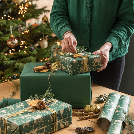 Une femme en train d'emballer des cadeaux de Noël