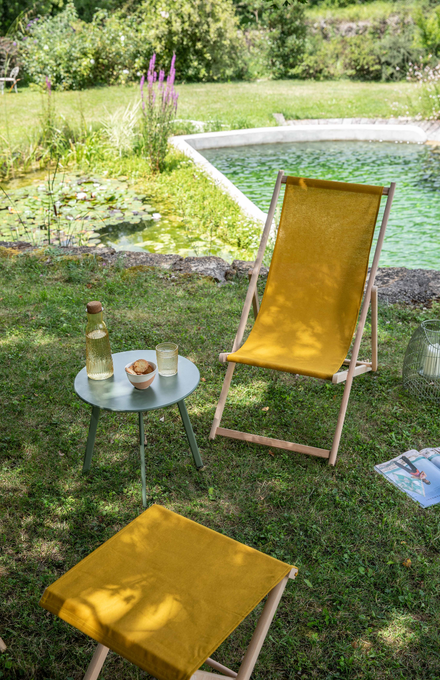 Une chilienne et son repose pied à l'ombre près d'une piscine