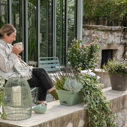 Une femme qui boit du thé sur son balcon d'automne