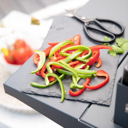 Des poivrons rouges et vert coupés avec un ciseaux sur une planche