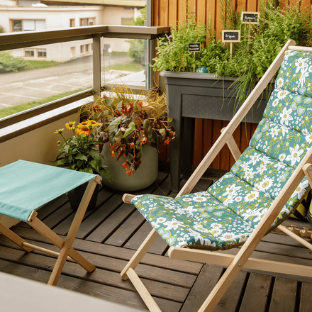 Un coin de détente amenagé sur un balcon avec une chilienne aux motifs fleuris