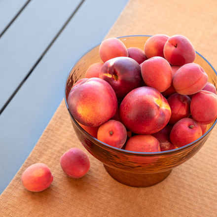 Des pêches dans un bol sur une table avec une nappe orange