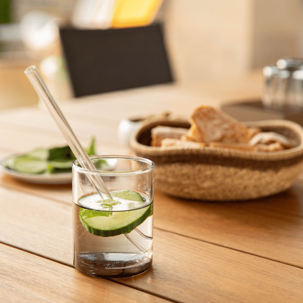 Un verre d'eau posé sur une table avec une rondelle de concombre