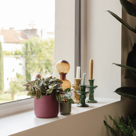 Un rebord de fenêtre décoré avec une plante en pot rose et des bougies