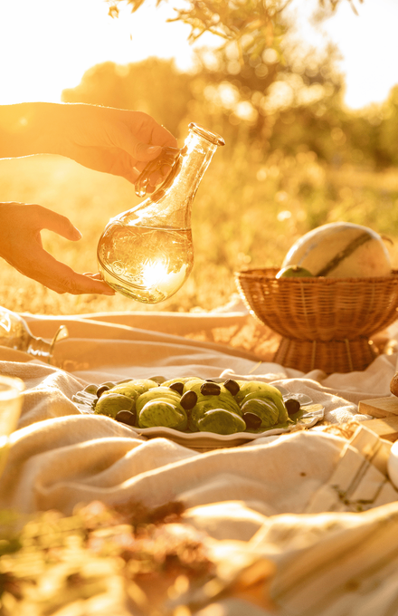 Une femme entrain de verser de l'huile sur sa salade de tomates vertes au cours d'un pique-nique sous un coucher de soleil