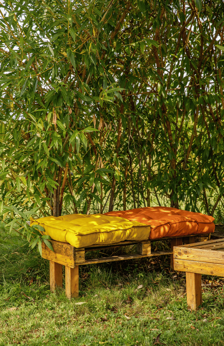 Un salon de jardin avec des coussins à l'ombre de bambou