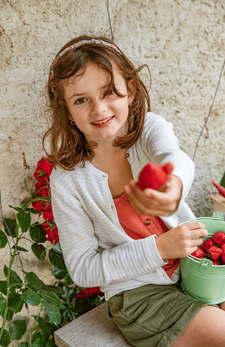 Une jeune fille en train de nous montrer une fraise du jardin