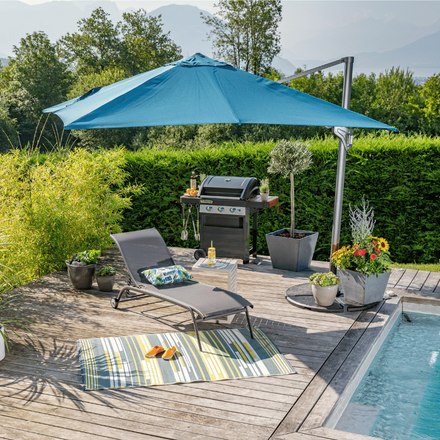 Parasol bleu déporté au bord de la piscine