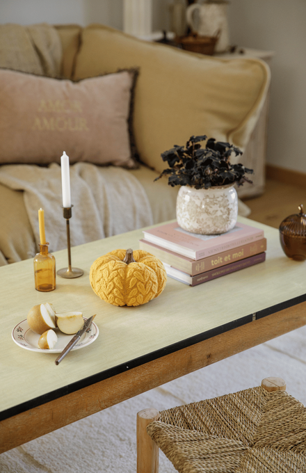 Un salon d'automne cosy avec des citrouilles, des bougies, des livres et des plantes