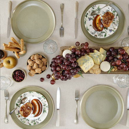 Vue de haut sur une table d'automne dressée avec des assiettes, des couverts et de la nourriture