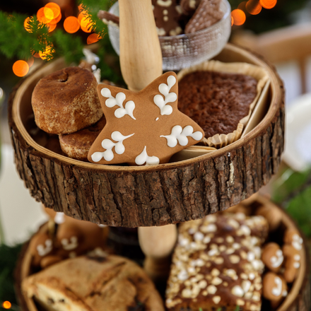 Des sablés et patisseries de noel disposés sur un plateau en rondin de bois